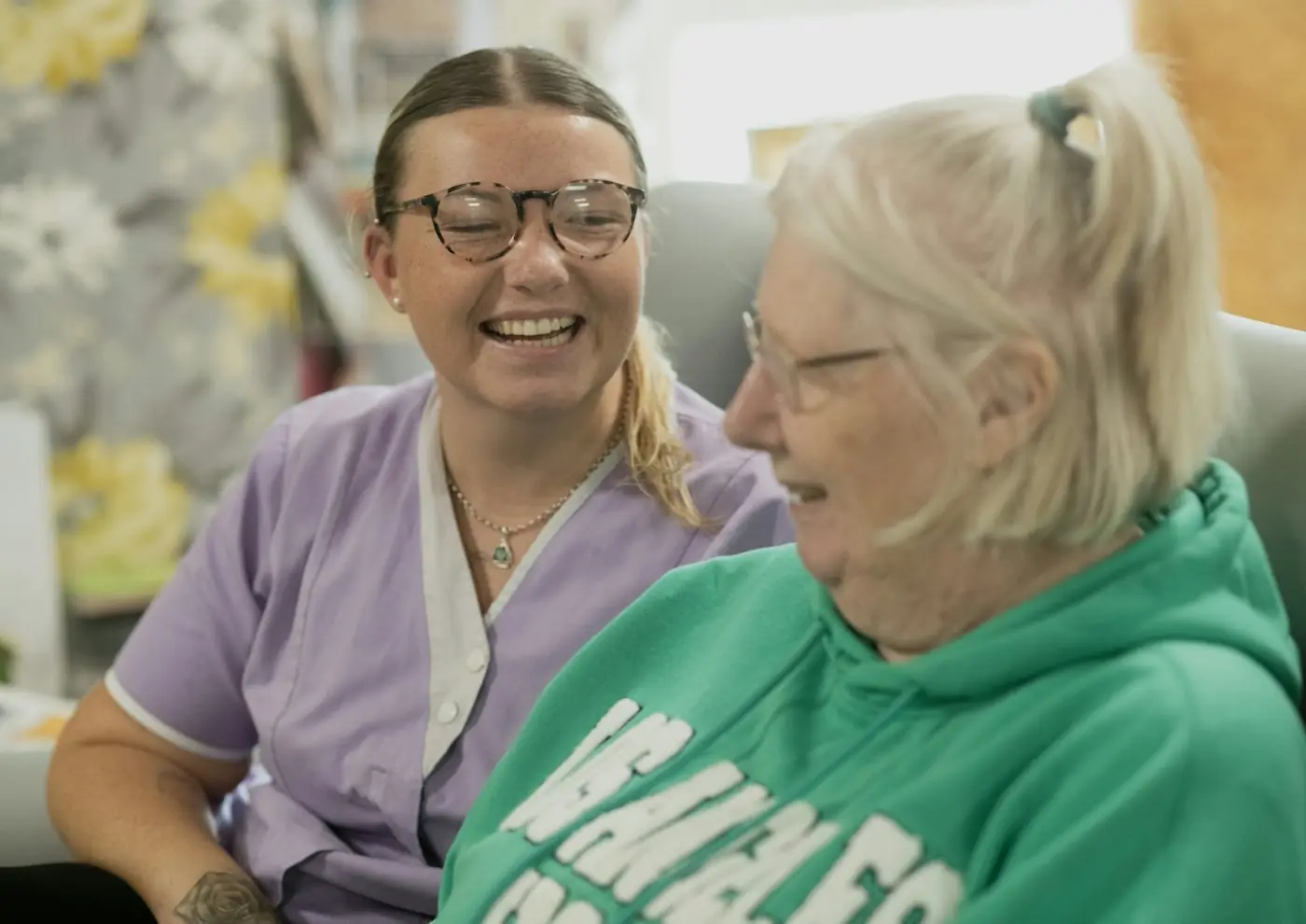 Support worker and older woman laughing together at home