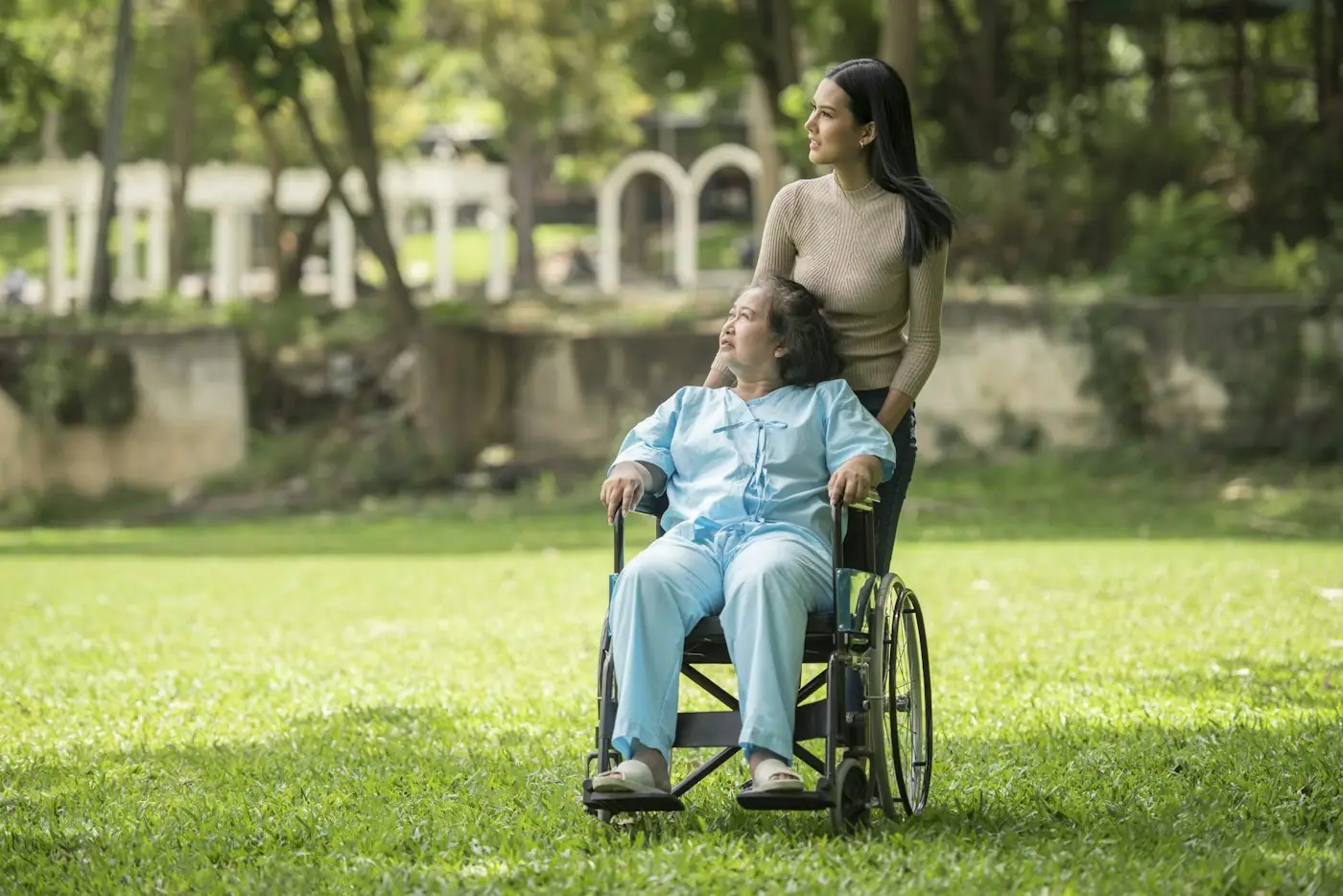 Older man in a wheelchair enjoying a park with a younger woman