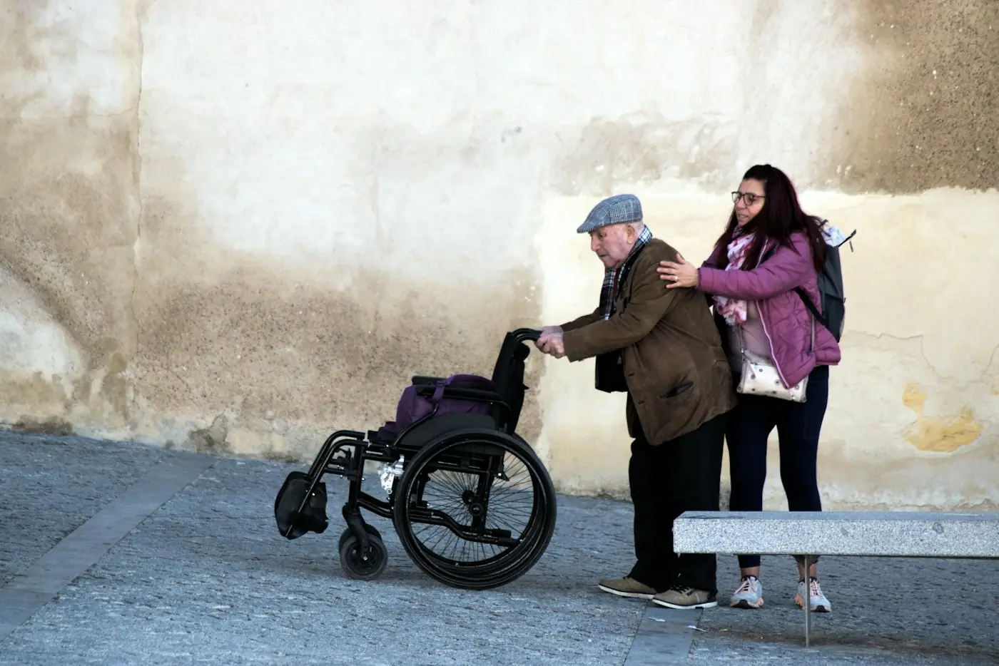 Young woman helping an older man in a wheelchair outdoors