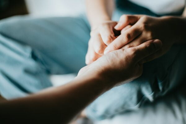 Two people holding hands in an in-depth look at comforting gestures.